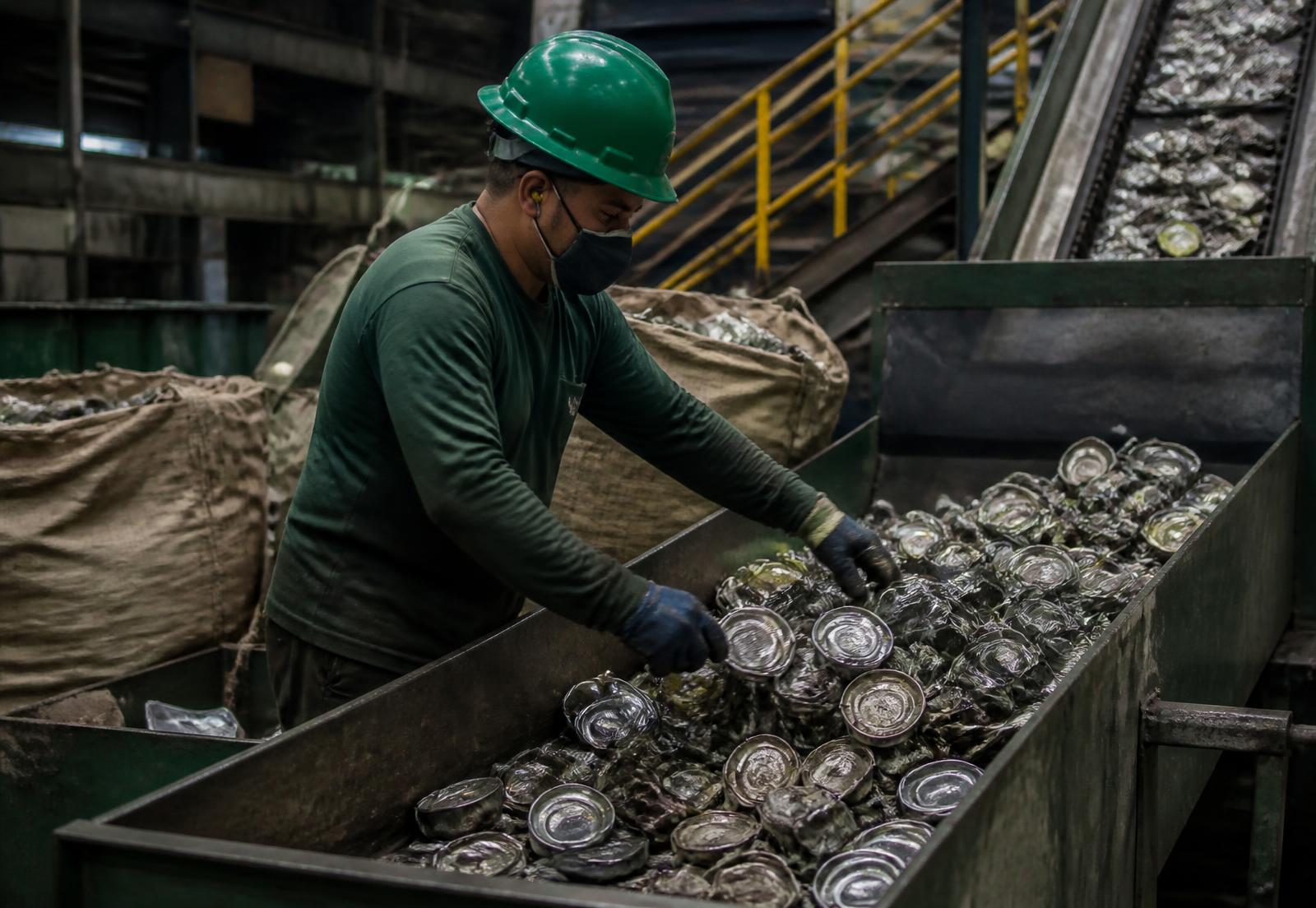 Trabalhador com equipamentos de segurança realizando triagem de materiais metálicos